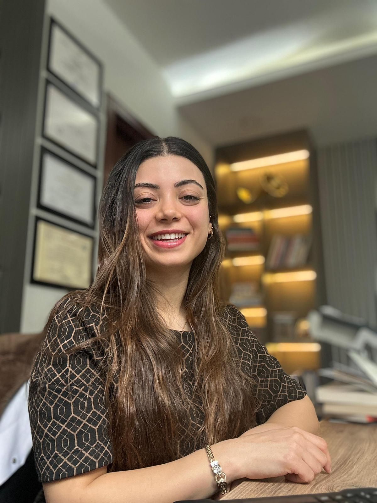 Diyetisyen Eylem Dizman, kliniğindeki çalışma masasında gülümsüyor